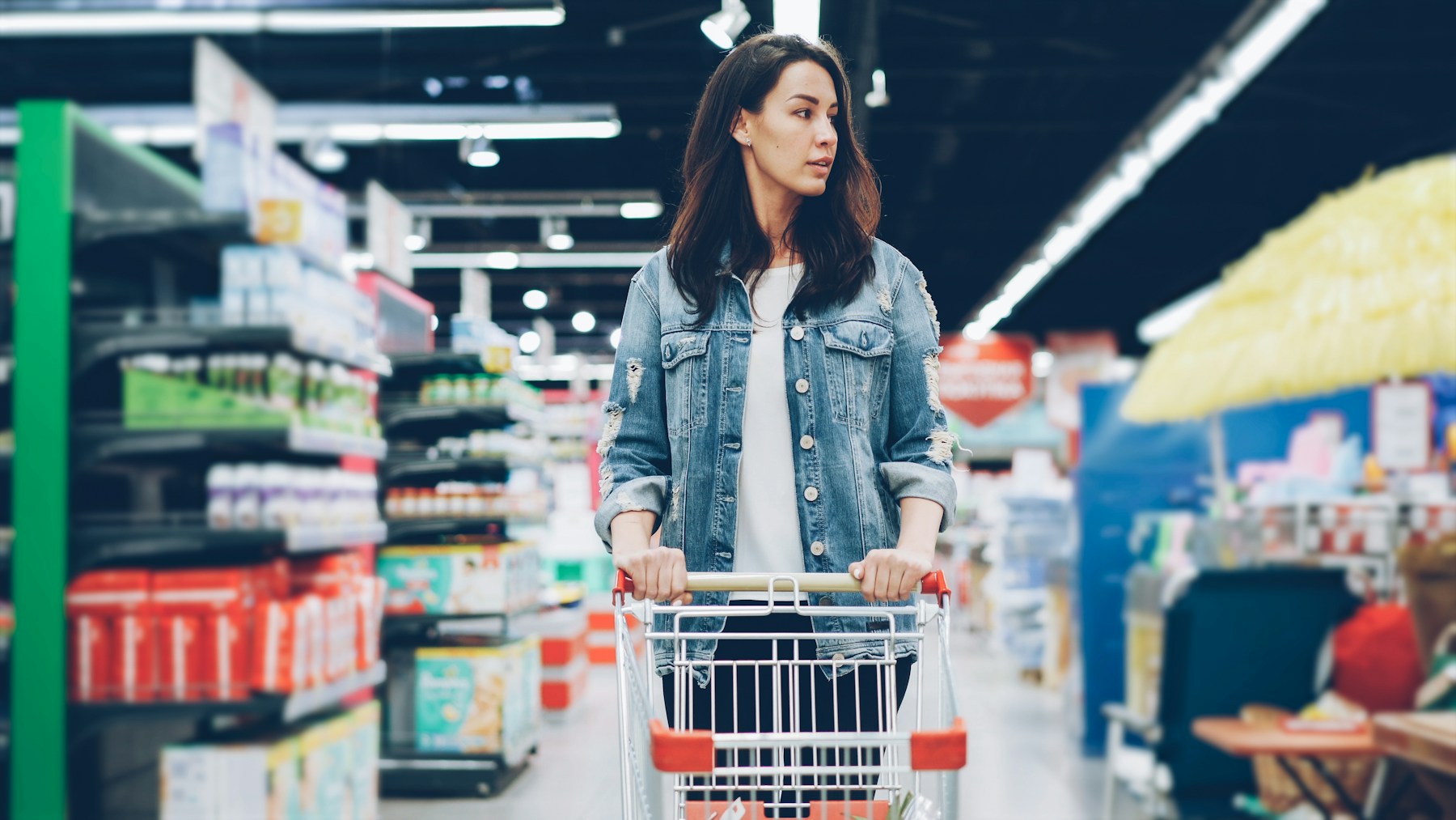 Cliente dans un rayon de supermarché comparant les produits avant de choisir un aliment sans gluten.